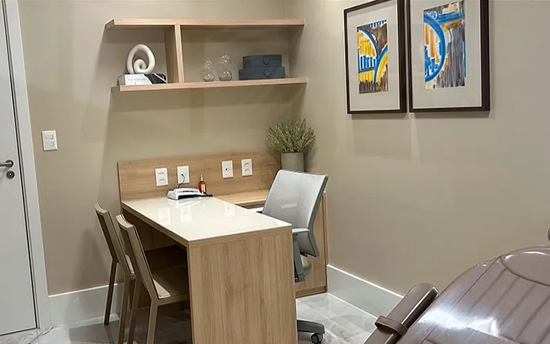 Sala de atendimento com mesa, quadros e poltrona de exame